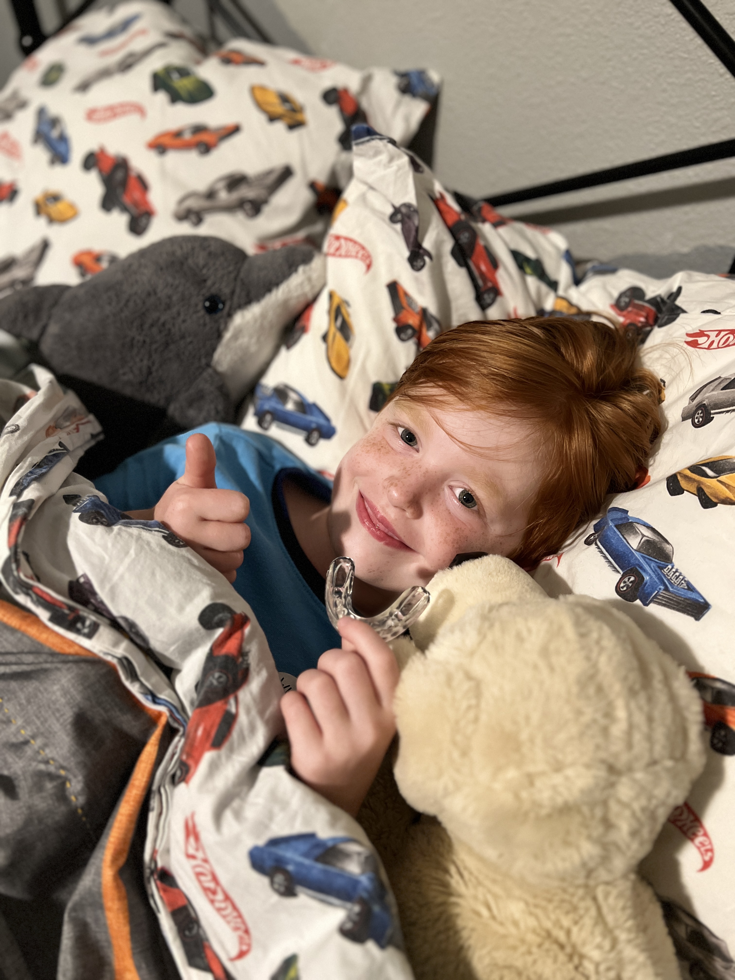 Young patient in bed giving a thumbs up while holding his Healthy Start appliance